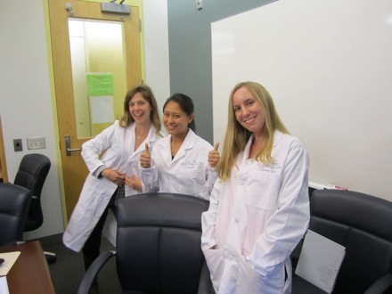 Peer mentors, Eden and Elaine, and TA, Kelli, proudly wear their white coats presented at Final Symposium.